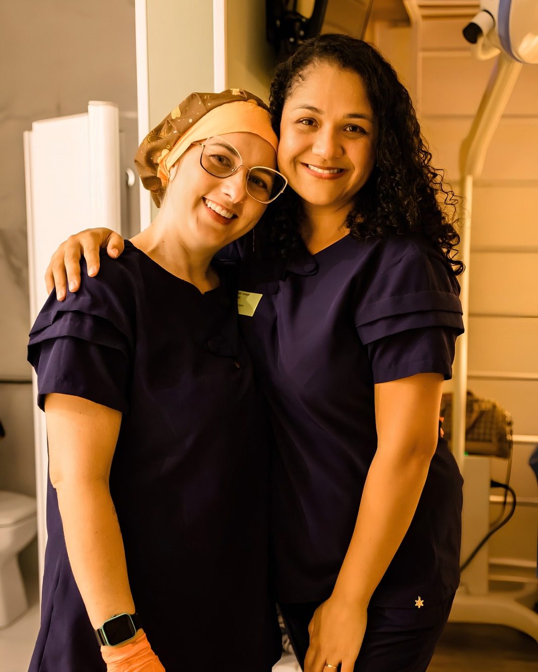 Manu e Stephanye abraçadas, de uniforme, sorrindo
