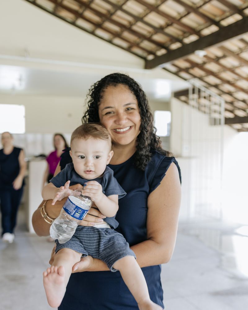 Stephanye sorrindo com um bebê no colo